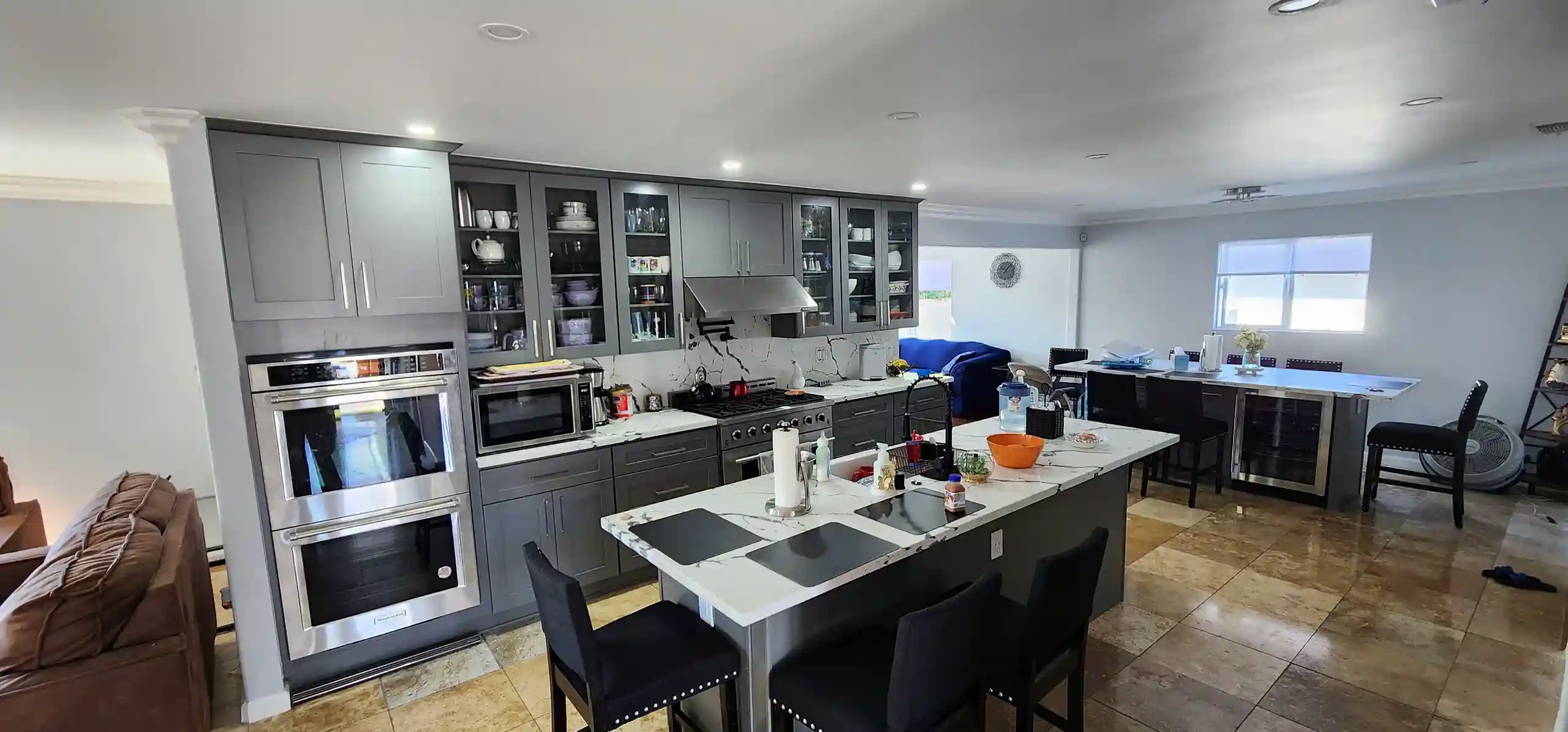 Modern gray kitchen renovation with marble island, stainless appliances and glass cabinets in Brooklyn NY